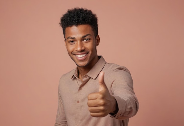 A young adult male with a bright smile gives a thumbs up to the camera hes wearing a casual buttonup