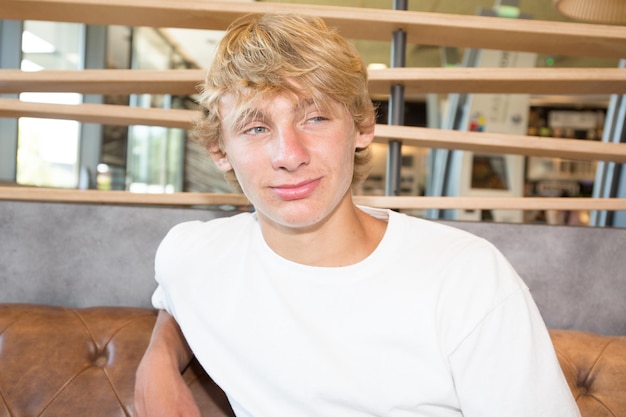 Young adult man indoors sitting sofa interior coffee bar. table