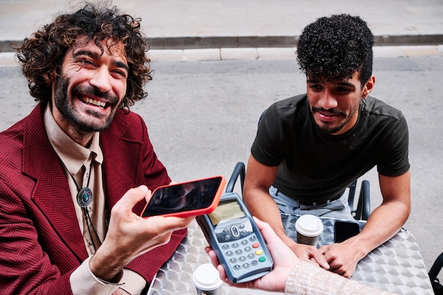 young adult man paying with mobile phone using a dataphone