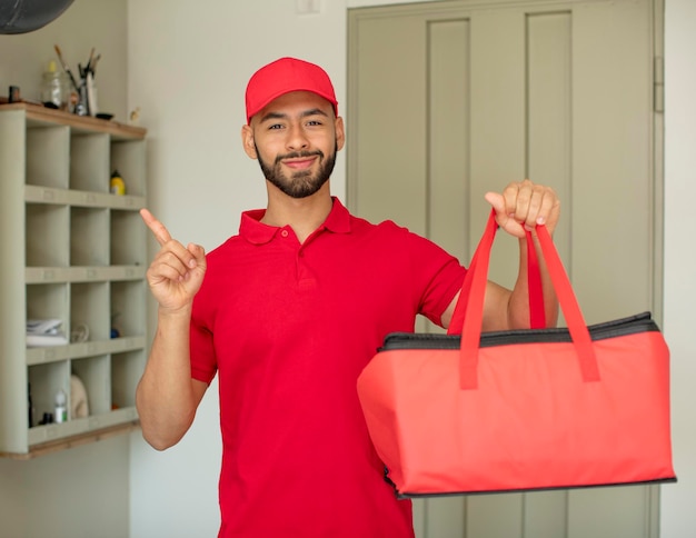 Foto giovane uomo adulto che sorride allegramente sentendosi felice e indicando il concetto di fattorino della pizza laterale