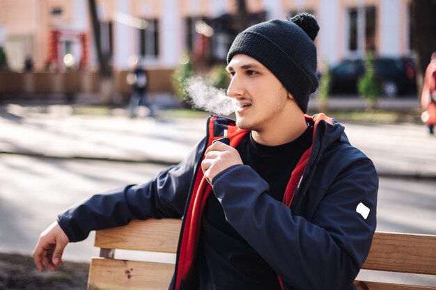 Молодой взрослый мужчина курит табачное устройство, электронная сигарета, нагреватель