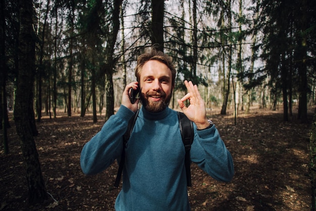 Young adult man talking on the phone standing at forest