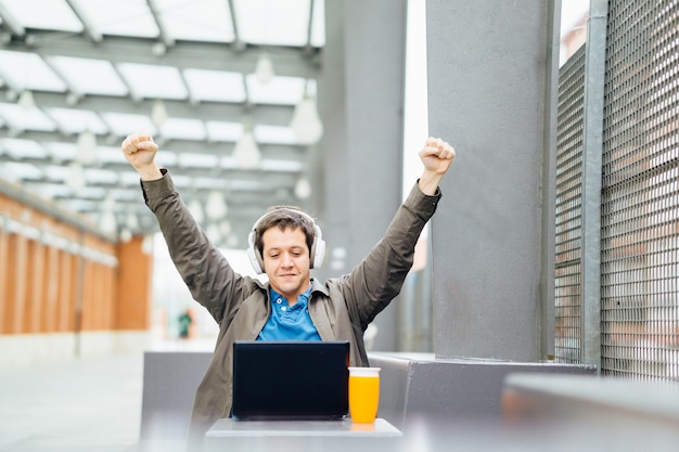 Young adult man working out on the street raising his arms in victory concept. concept work outside in good weather. laptop connectivity