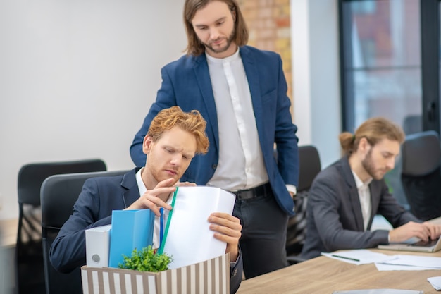 Young adult men in formal suits working busy in office at table with documents