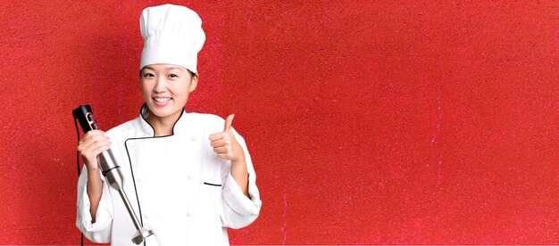 Photo young adult pretty asian woman restaurant chef with a hand blender