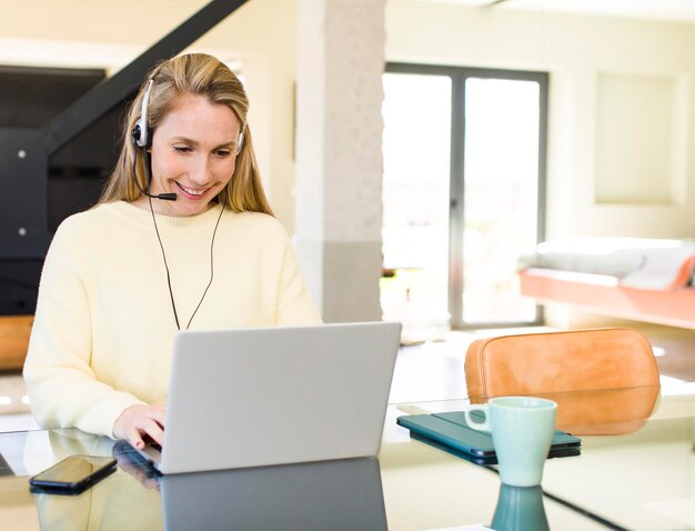 Young adult pretty blonde woman working at home teleconmmuting concept