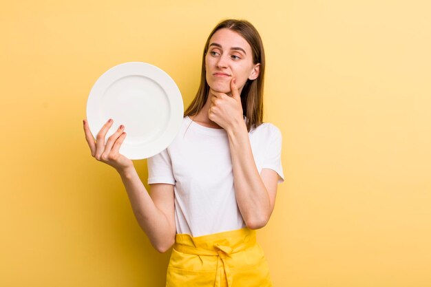 Молодой взрослый симпатичный шеф-повар женщина, держащая пустую тарелку