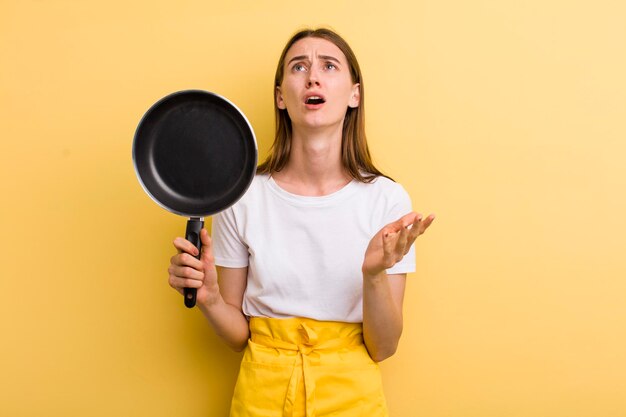 Young adult pretty chef woman with a pan