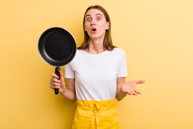 Young adult pretty chef woman with a pan