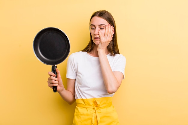 Young adult pretty chef woman with a pan