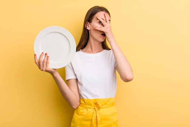 Young adult pretty woman chef with an empty dish