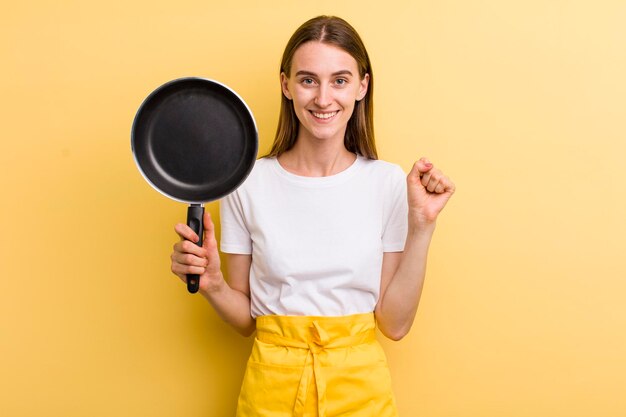 Young adult pretty woman chef with a pan