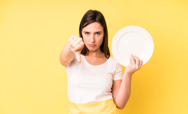 空のプレートを持つ若い大人のきれいな女性のホームシェフ