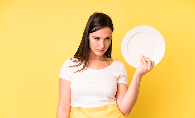 Young adult pretty woman home chef with empty plate