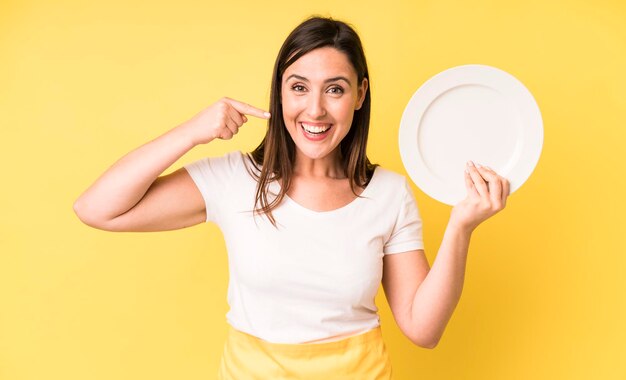 Young adult pretty woman home chef with empty plate