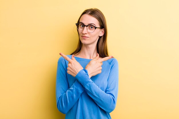 Young adult pretty woman isolated against yellow wall