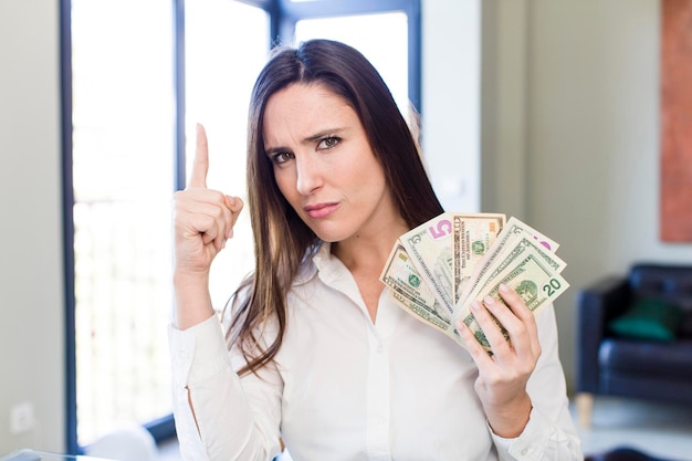 Young adult pretty woman with dollar banknotes at home