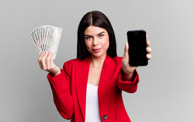 ドル紙幣と彼女のスマート フォンを示す若い大人のきれいな女性