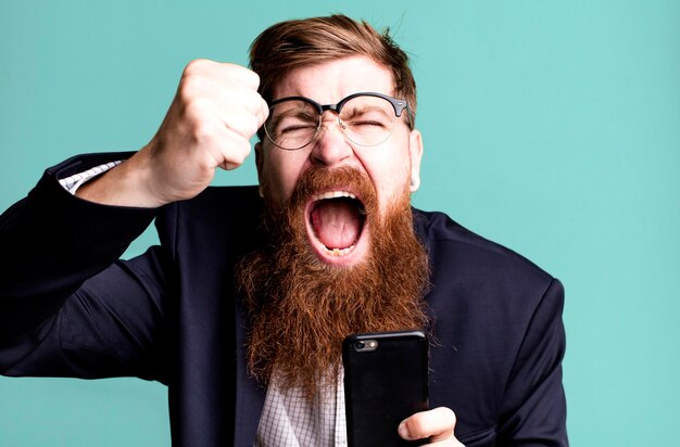 Photo young adult red hair bearded cool businessman using his smartphone