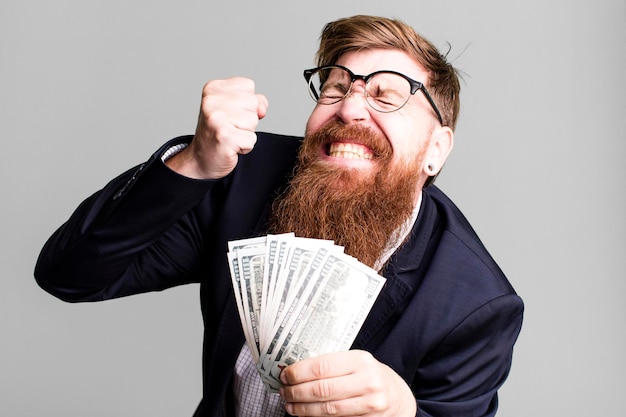 Photo young adult red hair bearded cool businessman with dollarbanknotes