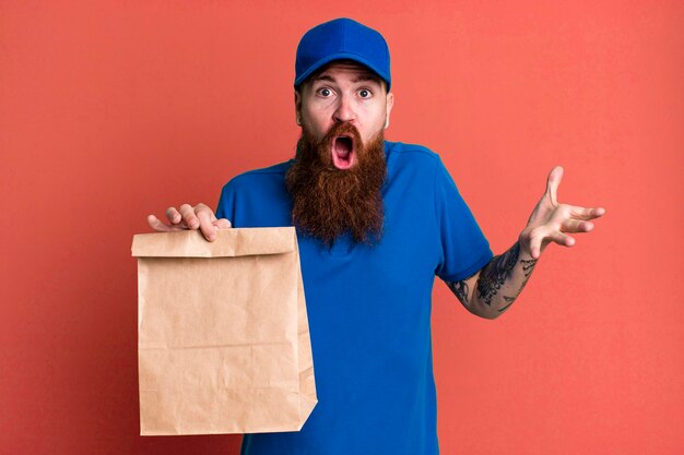 Young adult red hair bearded cool delivery man with a paper bag