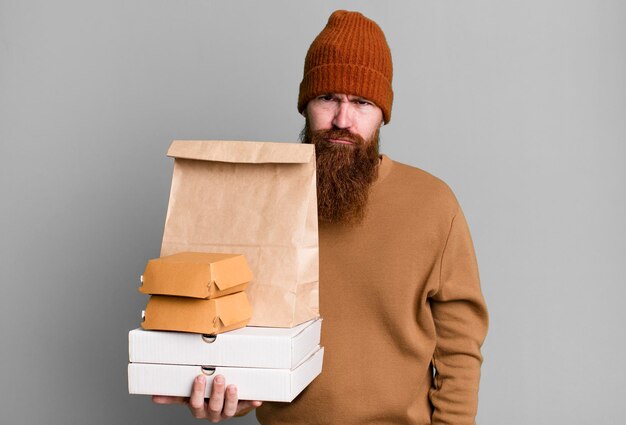 Young adult red hair bearded cool man with a paper bag with take away food