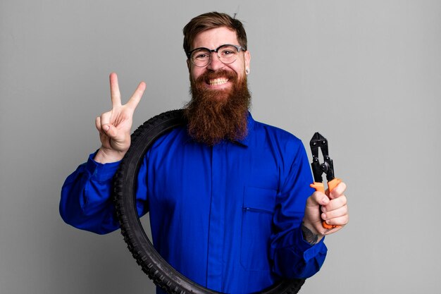 Young adult red hair bearded cool repair man with a bike wheel