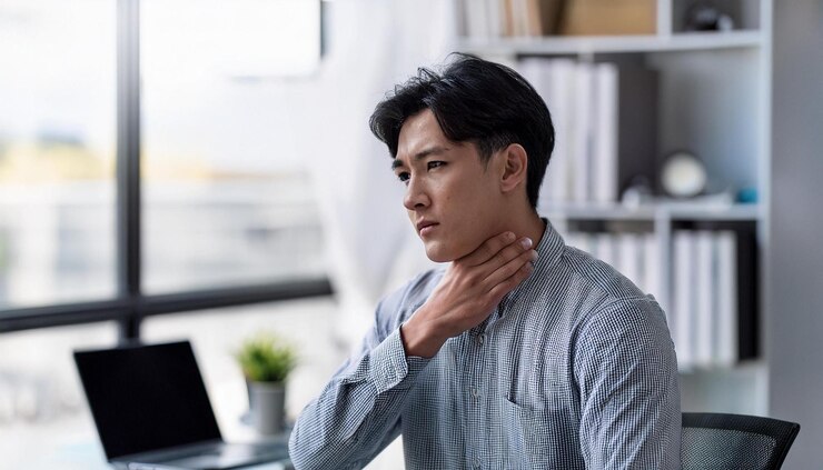 Photo 의사 사무실 에 앉아 있는 젊은 성인 이 걱정 스러운 표정 으로 목 을 부드럽게 만지고 있다