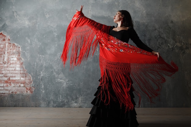 Young adult spanish woman dancing flamenco on gray vintage background