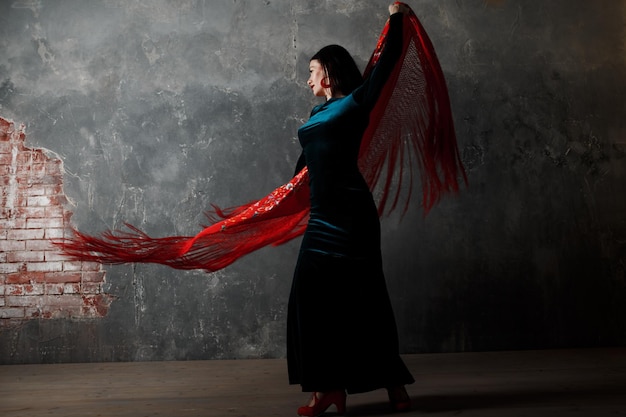 Молодая взрослая испанская женщина танцует фламенко на сером винтажном фоне