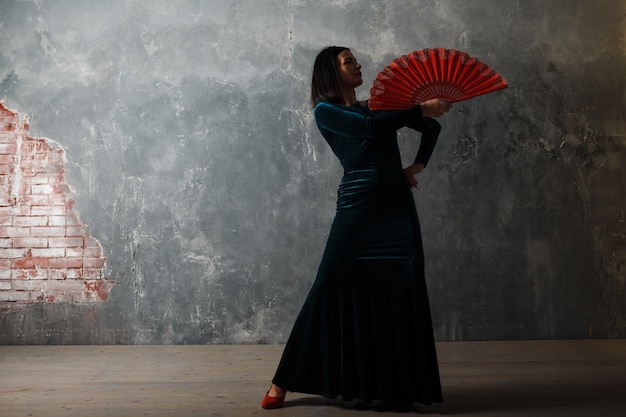 Young adult spanish woman dancing flamenco on gray vintage studio background