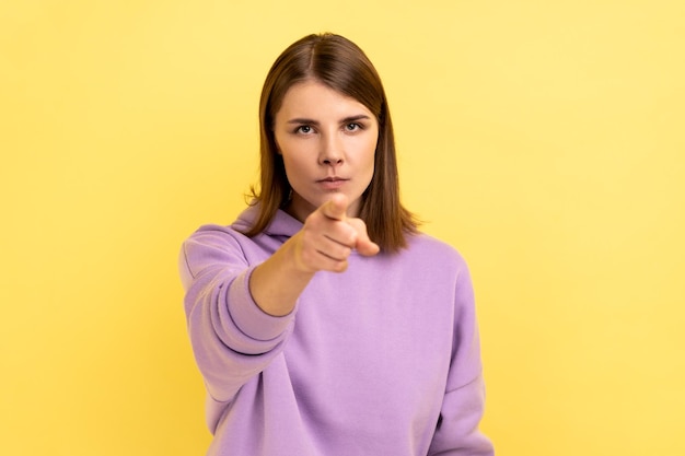Young adult strict bossy woman seriously pointing finger and looking at camera warning
