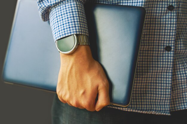 Photo young adult student in a shirt with a smartwatch holding a laptop