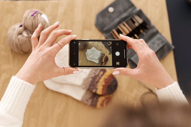 Photo young adult taking picture of their knitting product