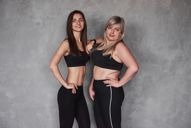 Young and adult. Two female friends with different body types and in sports wear standing