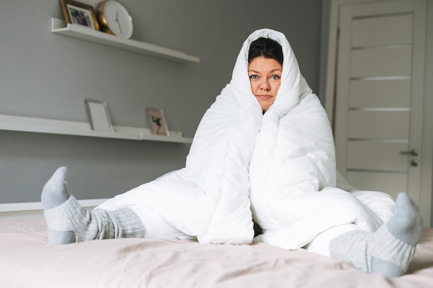 Foto giovane adulta infelice donna solitaria plus body size positiva in bianca grande coperta sul letto a casa