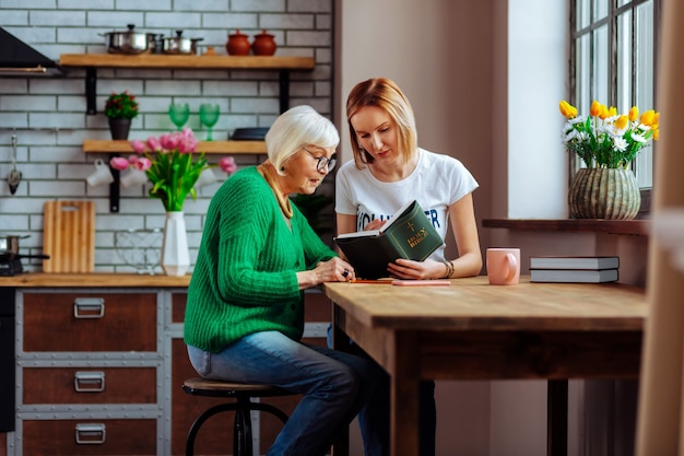 Photo young adult volunteer discussing with an aging woman in the kitchen