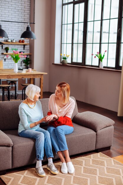 young adult volunteer discussing with an aging woman on sofa