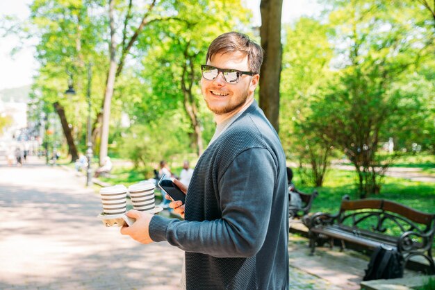 Foto giovane adulto che cammina con il caffè nel parco della città stile di vita giorno d'estate