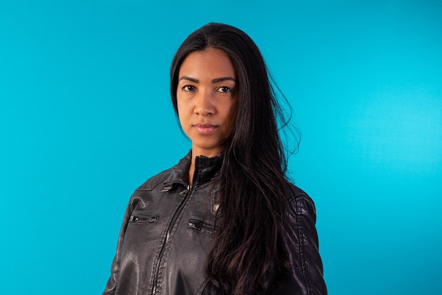 Young adult woman in black leather jacket in studio photo with blue background