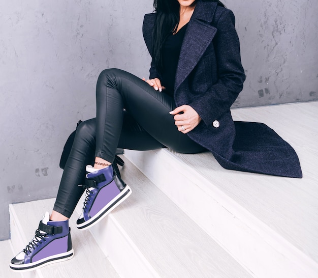 Photo a young adult woman in an elegant coat sits on the steps