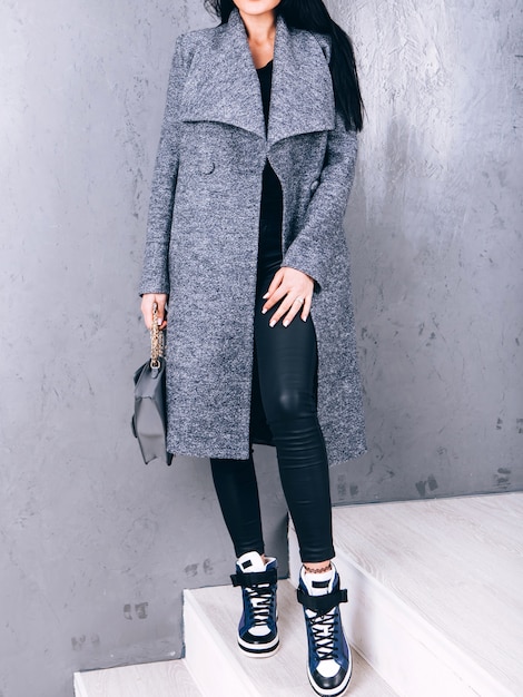 Young adult woman in an elegant coat and sneakers