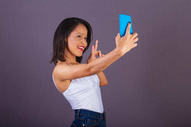 ブラジル北東部出身の若い成人女性が、オンラインでセルフ ポートレートの自撮り写真をスマートフォン アプリで撮っている