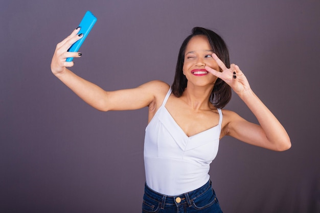 ブラジル北東部出身の若い成人女性が、オンラインでセルフ ポートレートの自撮り写真をスマートフォン アプリで撮っている