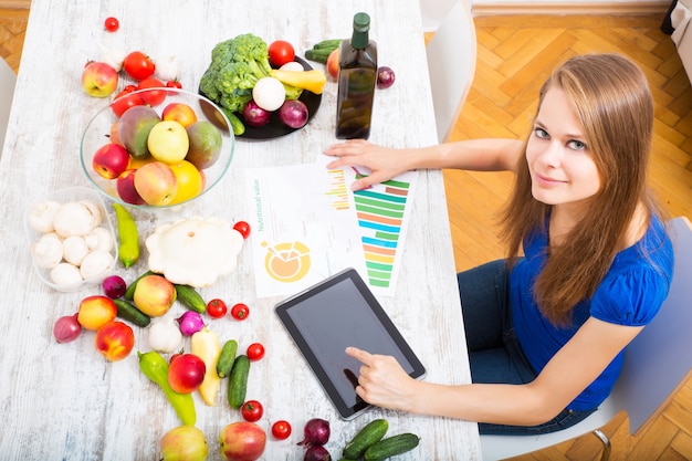 A young adult woman informing herself with a tablet PC about nutritional values of fruits