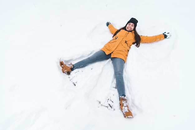 雪の天使を作る若い成人女性