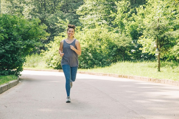 Young adult woman running by city park with music healthy lifestyle concept