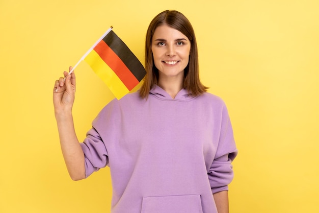 Young adult woman standing and waving german flag celebrating national holiday