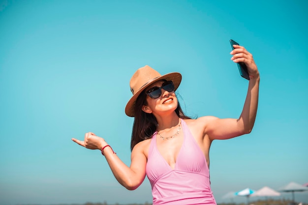 young adult woman takes a selfie on the beach on her vacation