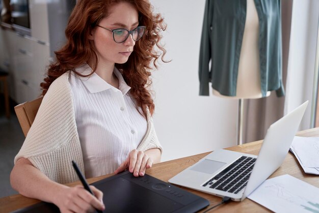 Young adult woman using laptop and designing a dress